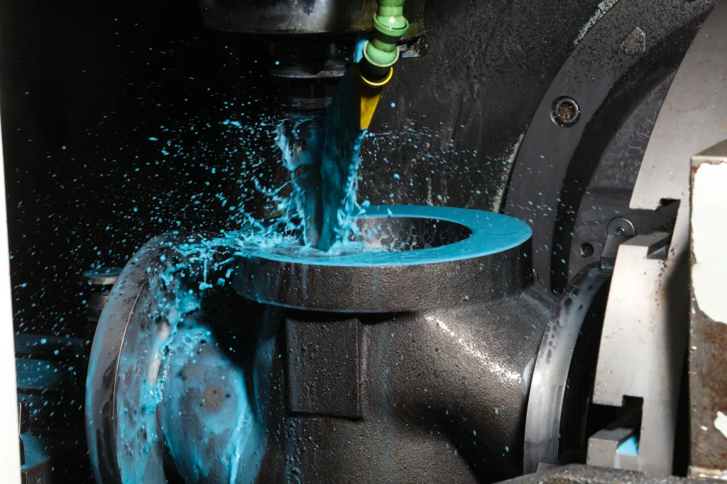 Coolant spraying over a valve body during CNC machining
